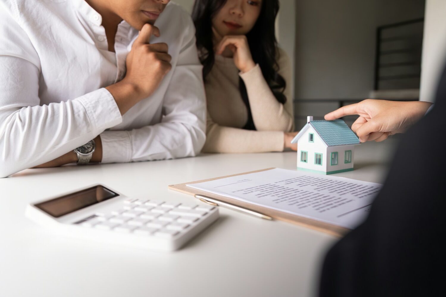 Young married couple sitting at table listening to realtor, real estate agent, loan broker or